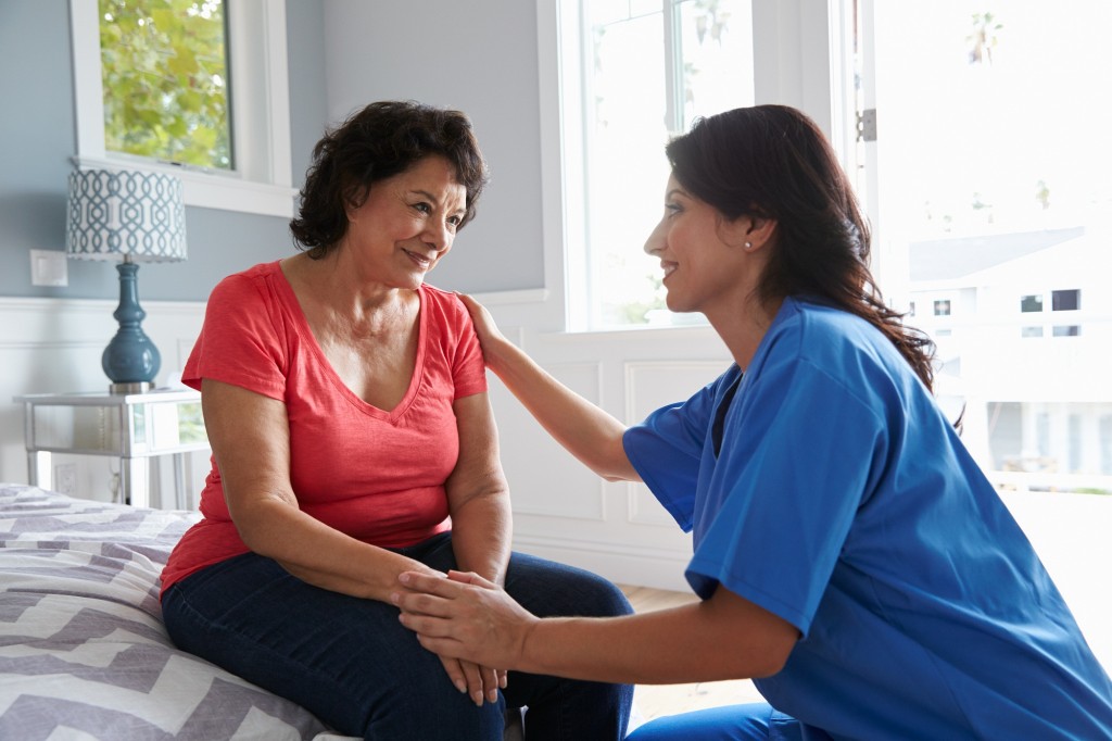 Nurse Making Home Visit To Senior Hispanic Woman